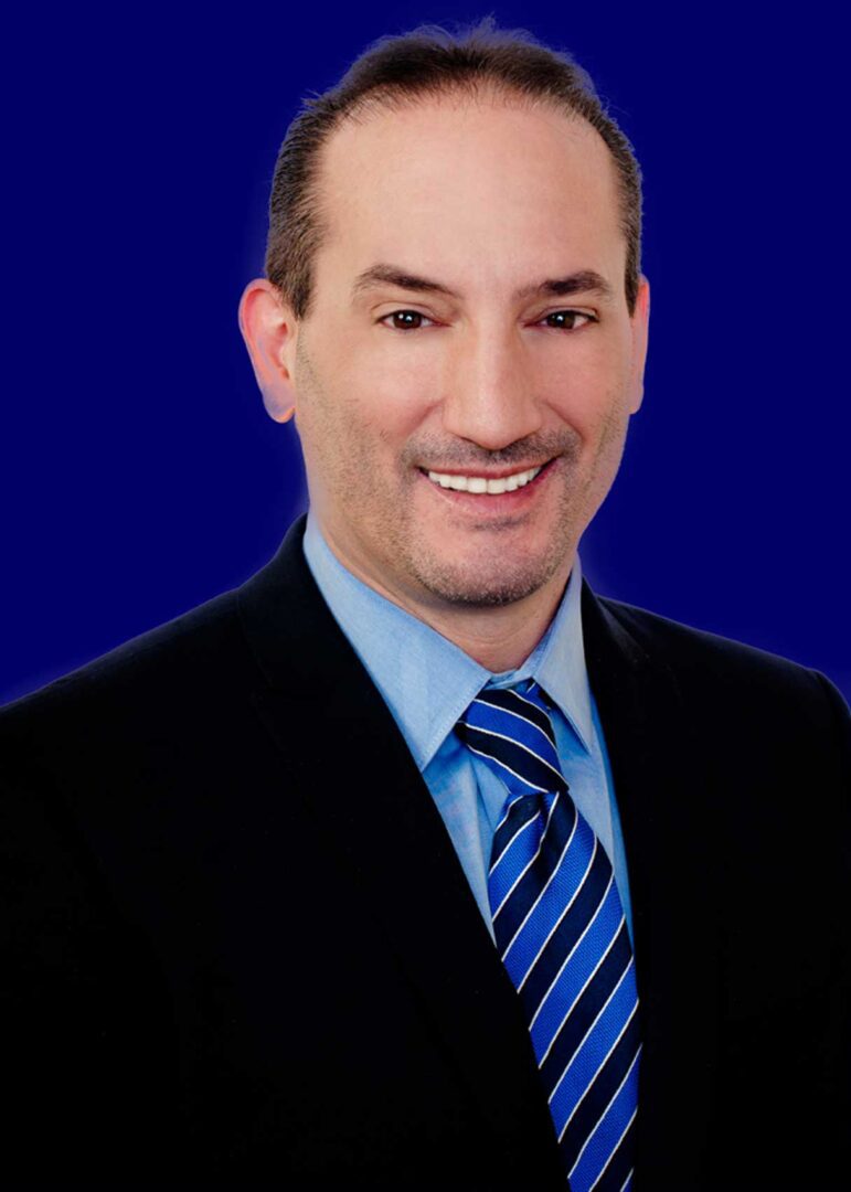 A man in a suit and tie smiling for the camera.