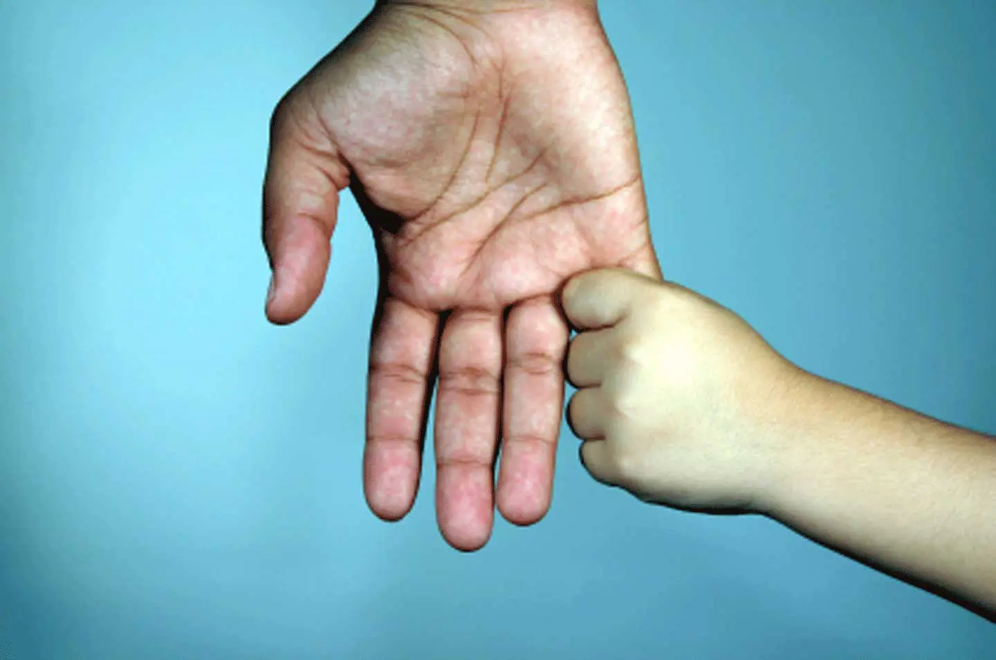 A child 's hand is touching the palm of an adult.