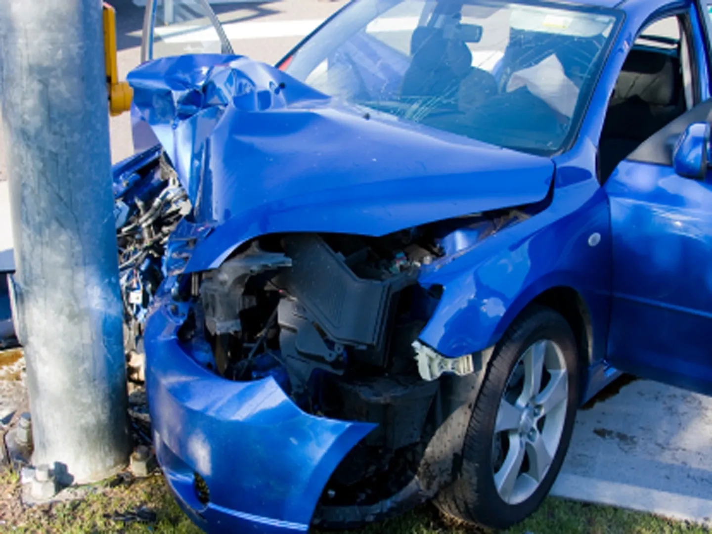 A blue car that has been smashed in the side of it.