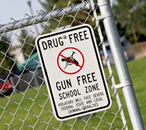 A sign warning people to not drink and drive is posted on the fence of a school.