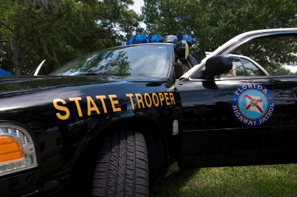 A state trooper car parked in the grass.