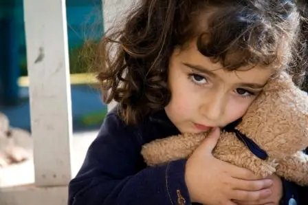 A little girl holding onto a teddy bear